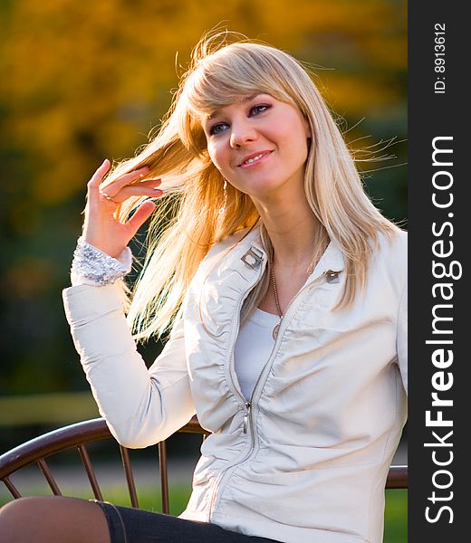 Pretty girl sitting on a bench in autumn park