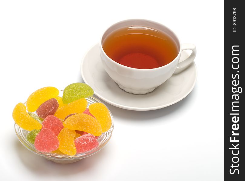 Fruit candy and tea cup. It is isolated on a white background