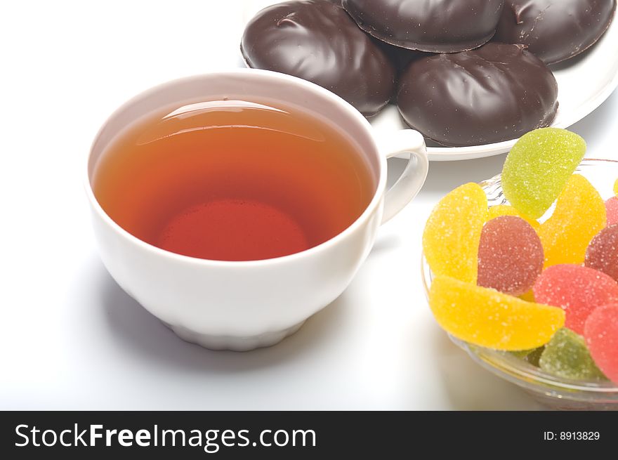 Mug with tea a marshmallow and colour fruit candy close up. Mug with tea a marshmallow and colour fruit candy close up