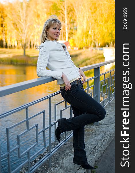 Pretty girl in white jacket near fence of a bridge - shallow DOF