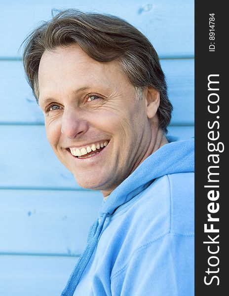 A happy smiling forties man having fun at the beach and standing in front of a hut. A happy smiling forties man having fun at the beach and standing in front of a hut.