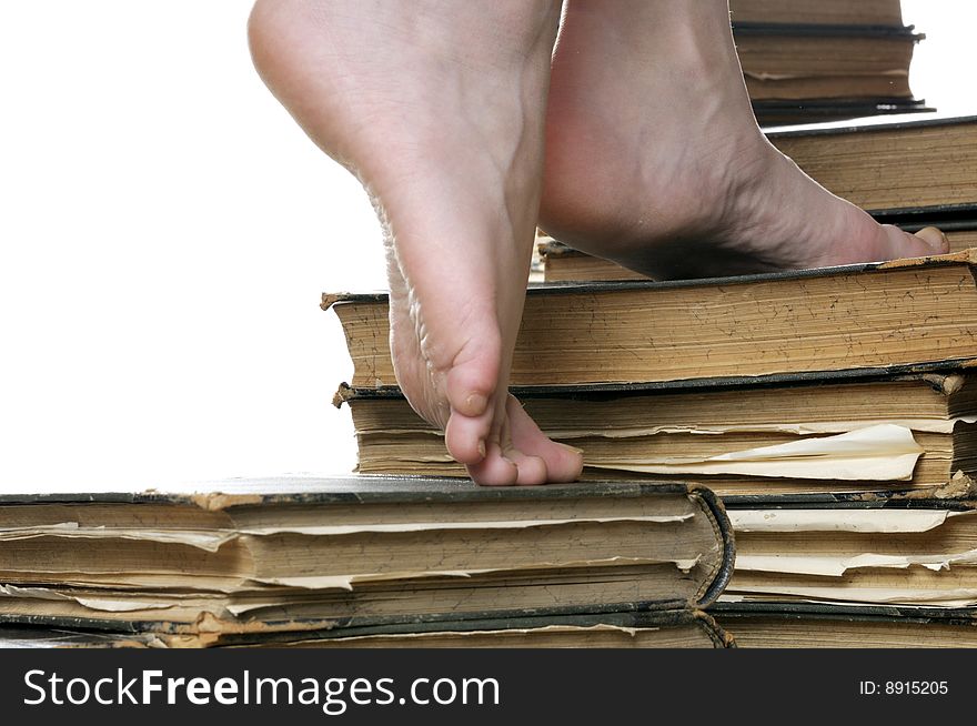 Girls feet stepping on stairway build from ancient books, isolated on white background. Girls feet stepping on stairway build from ancient books, isolated on white background