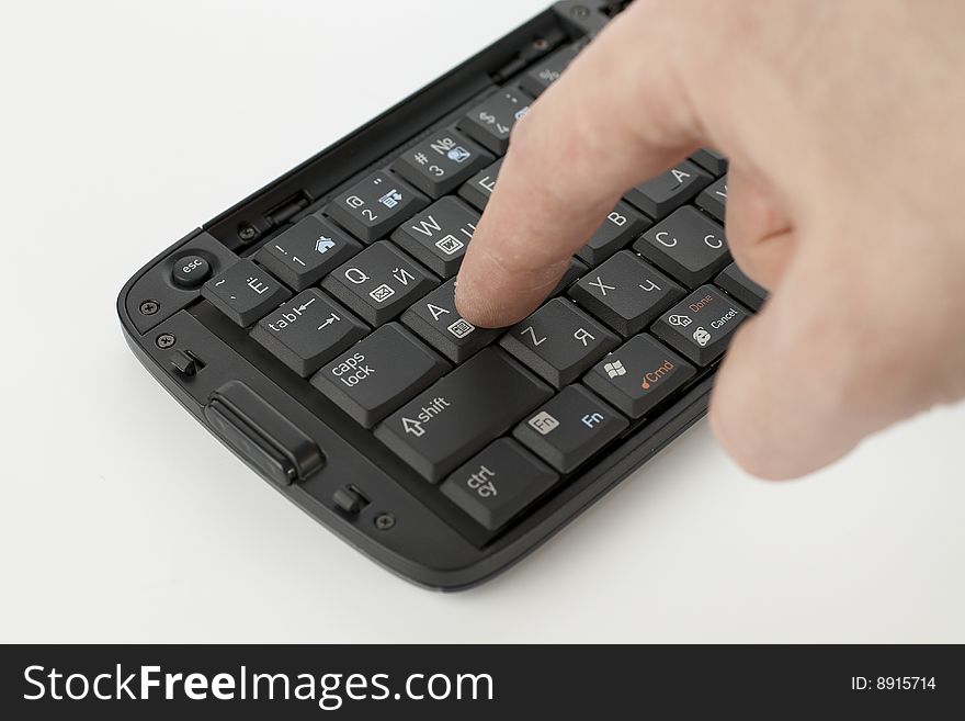 Finger pushing button on compact black keyboard. Finger pushing button on compact black keyboard