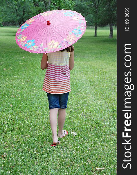 Beautiful 10 year old brown haired girl holding a parasol outdoors in the park. Beautiful 10 year old brown haired girl holding a parasol outdoors in the park