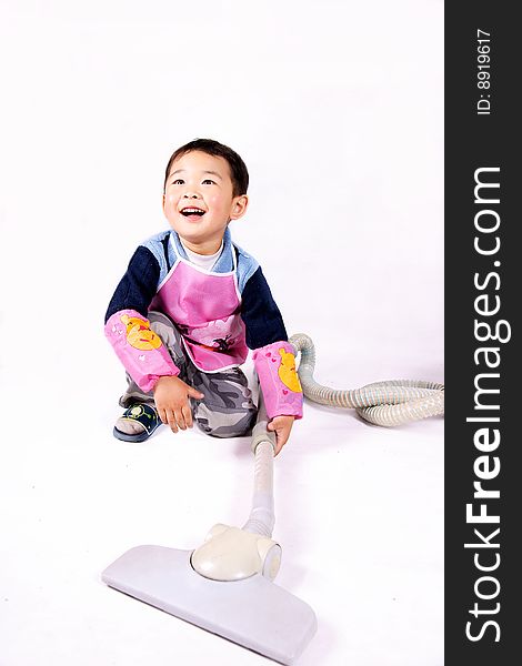 A picture of a little chinese boy playing with vacuum cleaner wearing apron. A picture of a little chinese boy playing with vacuum cleaner wearing apron