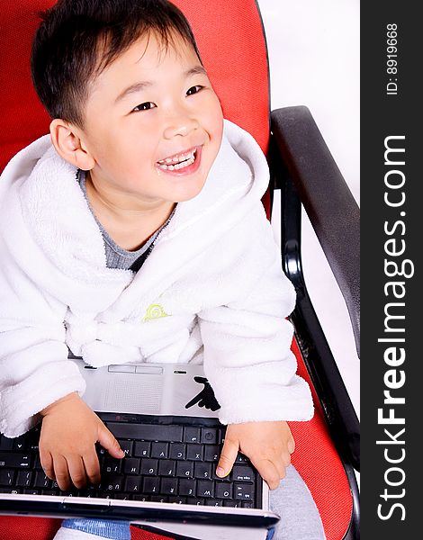 A picture of a little chinese boy playing with a notebook happily while wearing bathrobe. A picture of a little chinese boy playing with a notebook happily while wearing bathrobe