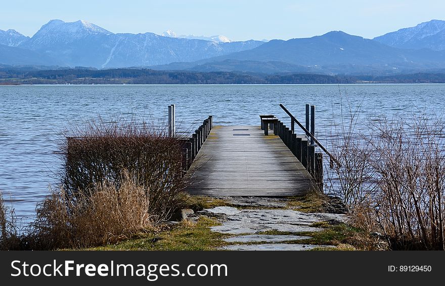 A pier leading off into the water with mountains in the horizon. A pier leading off into the water with mountains in the horizon.