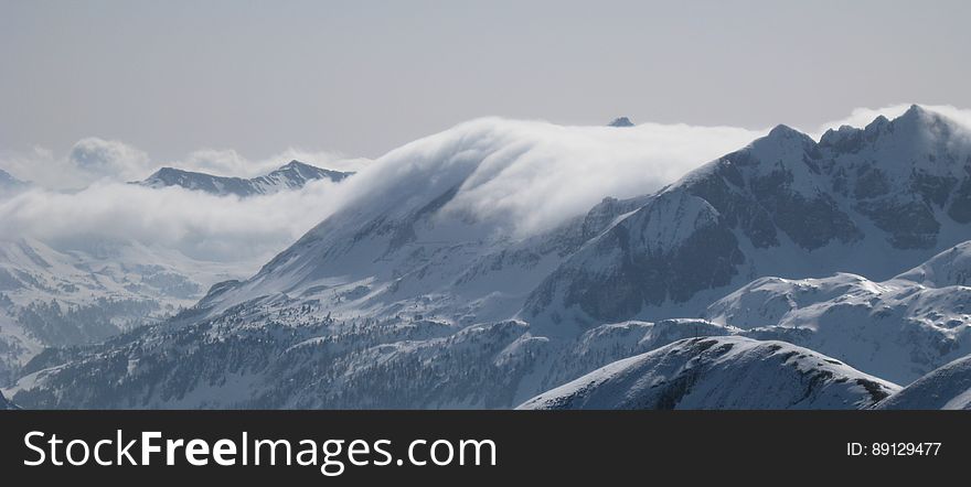 A snowy mountain range with clouds covering the peaks. A snowy mountain range with clouds covering the peaks.