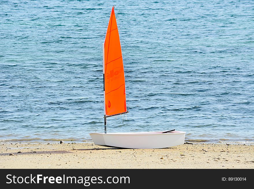 A single sail boat on sandy beach. A single sail boat on sandy beach.