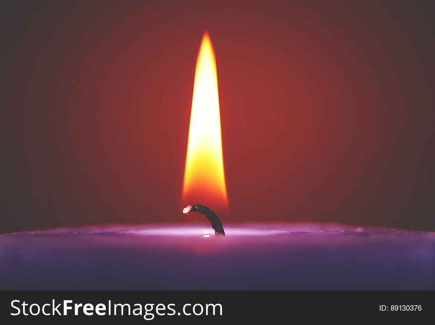 A close up of a burning violet candle. A close up of a burning violet candle.