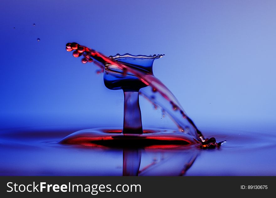 A close up of a water drop splashing on a water surface.