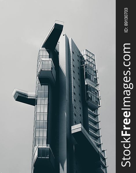 A black and white photo of a modern high rise building from a low angle.