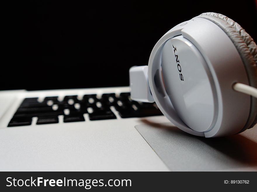 A close up of headphones and a computer keyboard in the background.