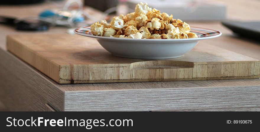 A bowl of popcorn on a plate on kitchen counter.