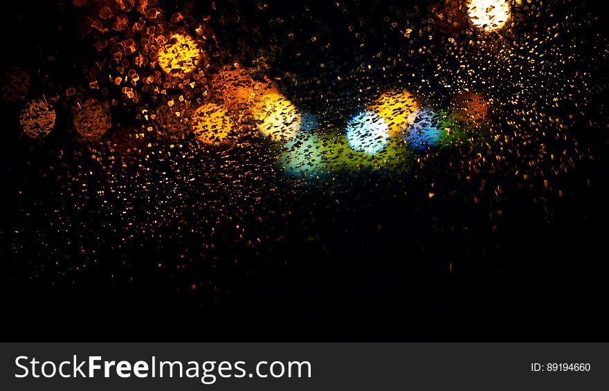 Colorful bokeh lights behind window with raindrops. Colorful bokeh lights behind window with raindrops.