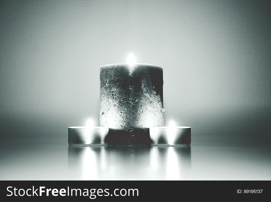 Monochrome view of group of large and small burning candles. Monochrome view of group of large and small burning candles.