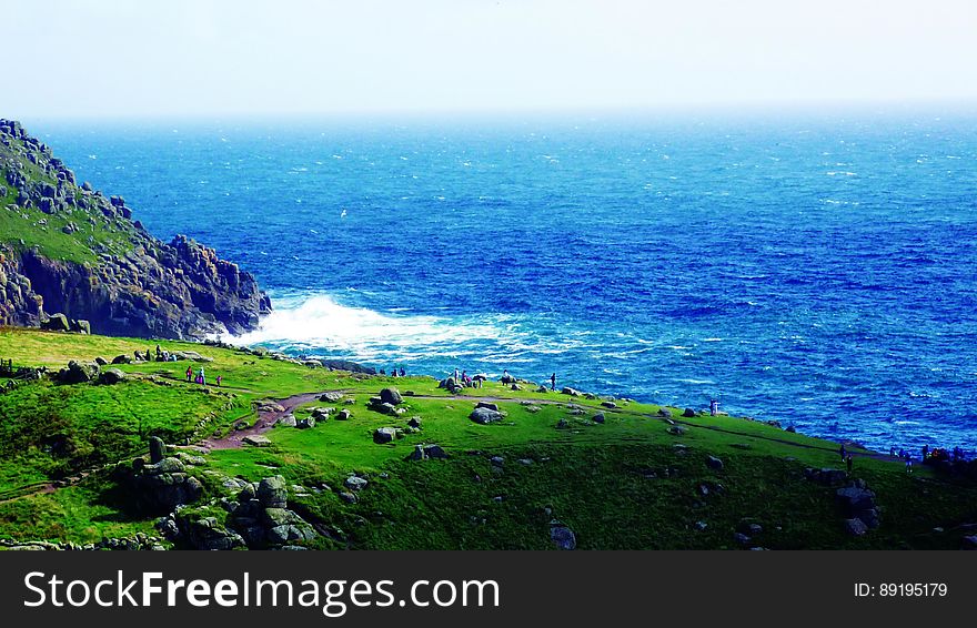 A view of a sea coast with green meadows and rock cliffs.