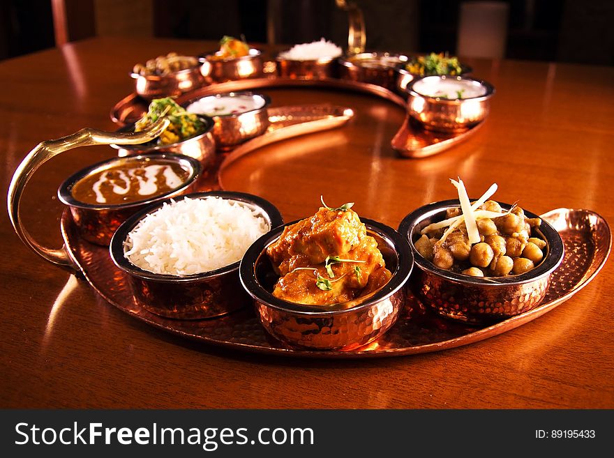 Copper tray with bowl of Indian dishes on wooden tabletop. Copper tray with bowl of Indian dishes on wooden tabletop.