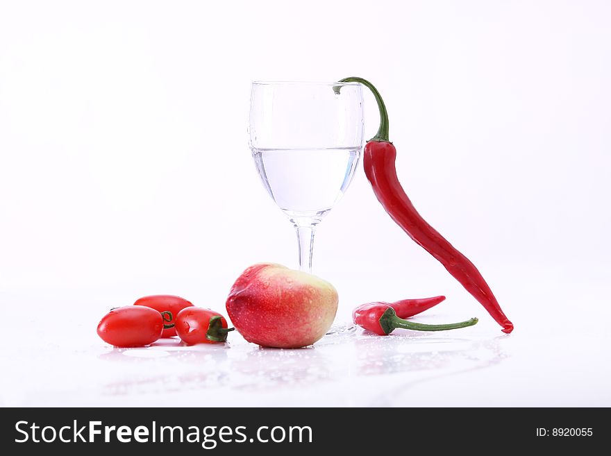 Peachs , peper and tomatoes on white background with goblet, water in it. Peachs , peper and tomatoes on white background with goblet, water in it