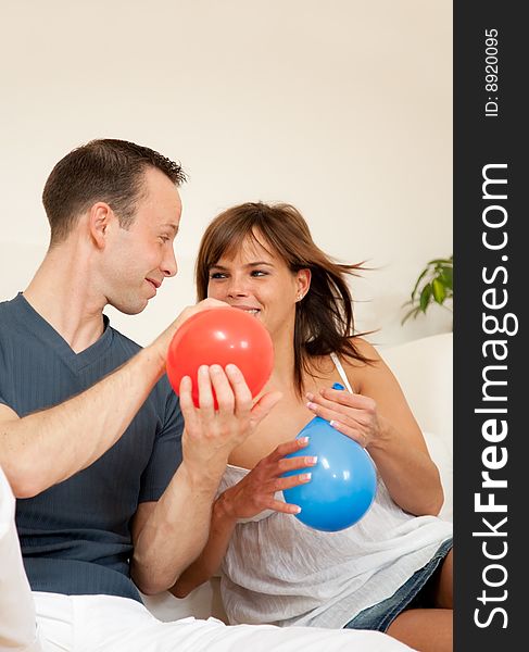 Young man and woman blowing ballons for party. Young man and woman blowing ballons for party