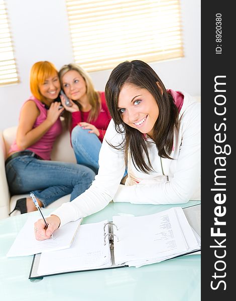 Happy three girls. One of them doing homework. Blonde and red-haired talking by cellphone. Focused on brunette girl. Happy three girls. One of them doing homework. Blonde and red-haired talking by cellphone. Focused on brunette girl.