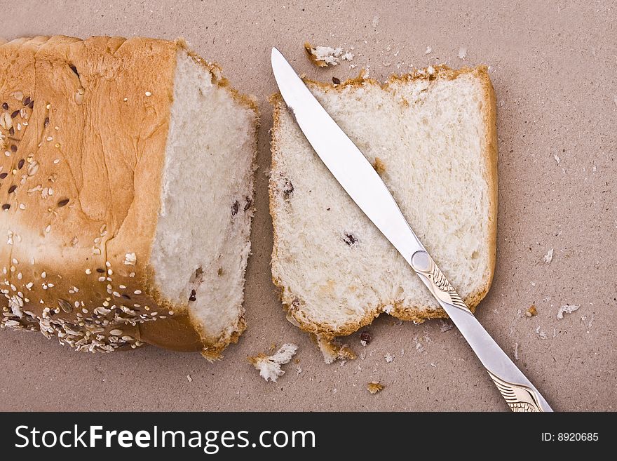 White background, bread in peieces, covered with til seed, cornmeal with knife on side. White background, bread in peieces, covered with til seed, cornmeal with knife on side