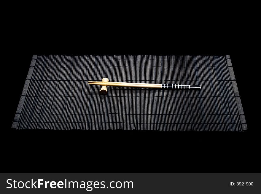 Japanese chopsticks on bamboo mat on black background