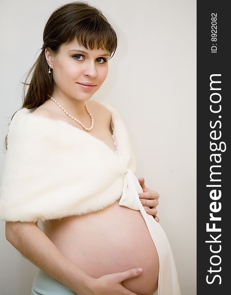 Portrait of young pregnant woman in white wearing