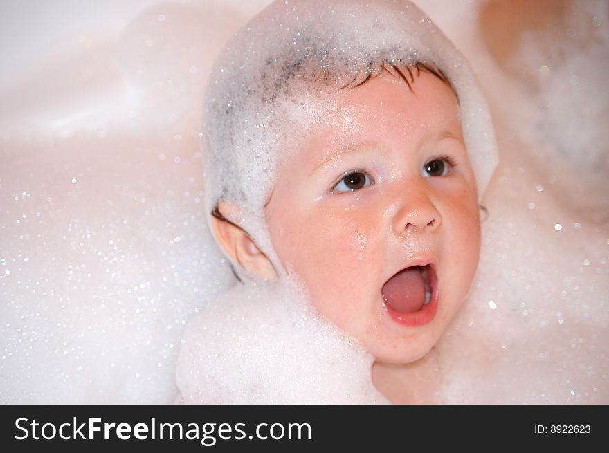 The little girl bathes in soapsuds