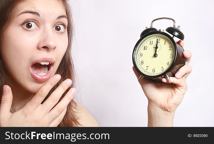 Portrait of the scared girl holding an alarm clock in a hand. Portrait of the scared girl holding an alarm clock in a hand.