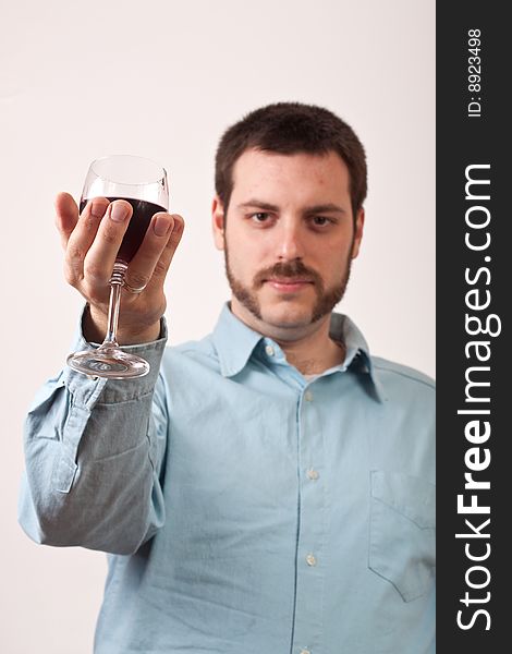 Young man holding a glass of red wine with focus on glass. Young man holding a glass of red wine with focus on glass