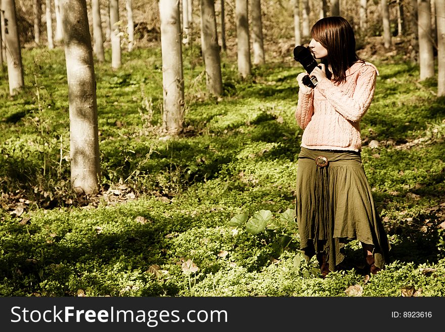 Young pretty female photographer in a forest.