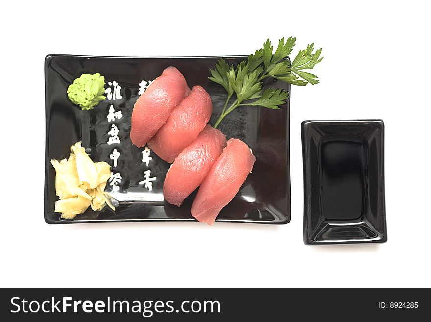 A set of sushi on a black plate with wasabi and gari, isolated on a white background. A set of sushi on a black plate with wasabi and gari, isolated on a white background.