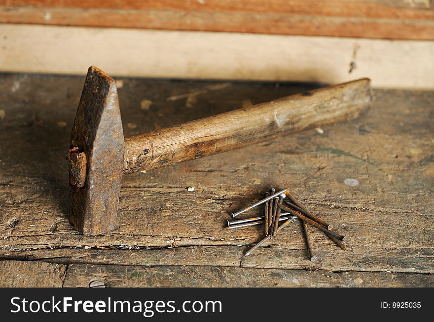 Old rusty hammer and nails on wooden table, focus on nails