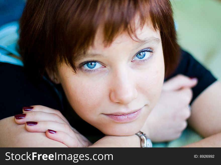 The girl looks expressive blue eyes, a blue T-shirt, hands folded. The girl looks expressive blue eyes, a blue T-shirt, hands folded