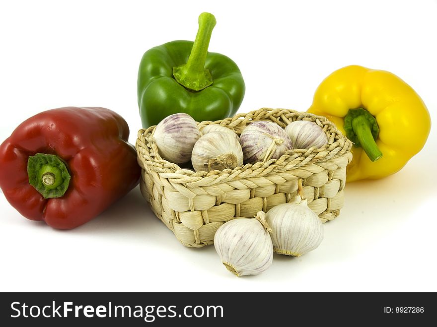 Three bell peppers and basket full of fresh garlics isolated on white background. Three bell peppers and basket full of fresh garlics isolated on white background