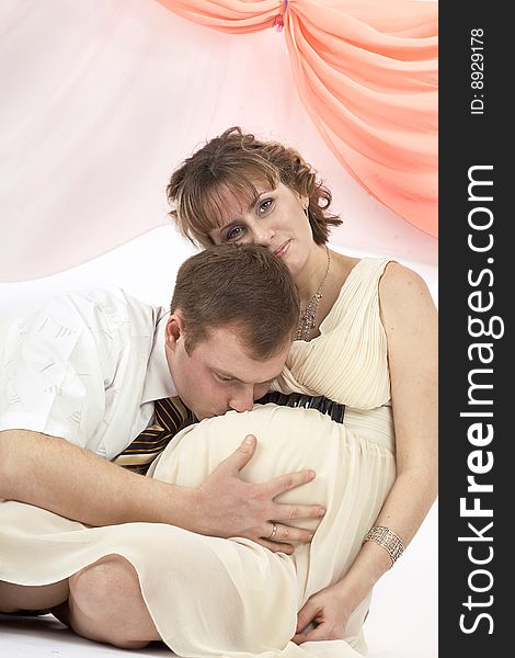 Young beautiful married couple the birth of the first child wait. Pink background. New photos every week