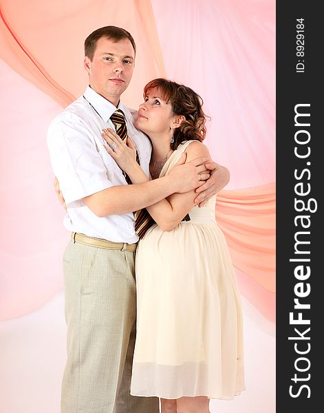 Young beautiful married couple the birth of the first child wait. Pink background. New photos every week