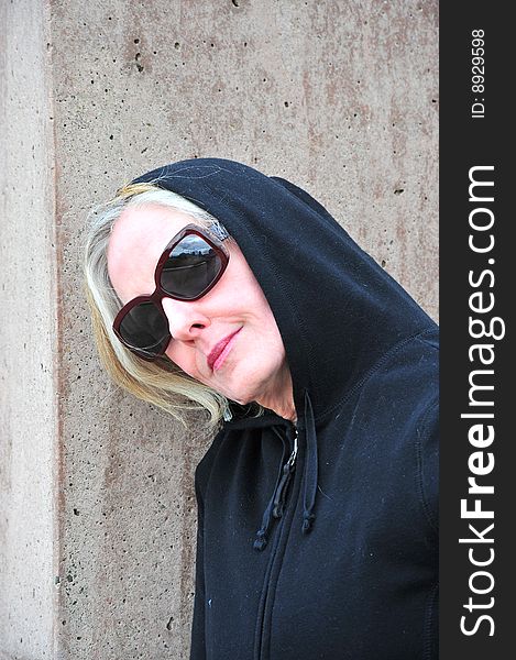 Portrait of a mystery woman standing next to a wall outdoors.