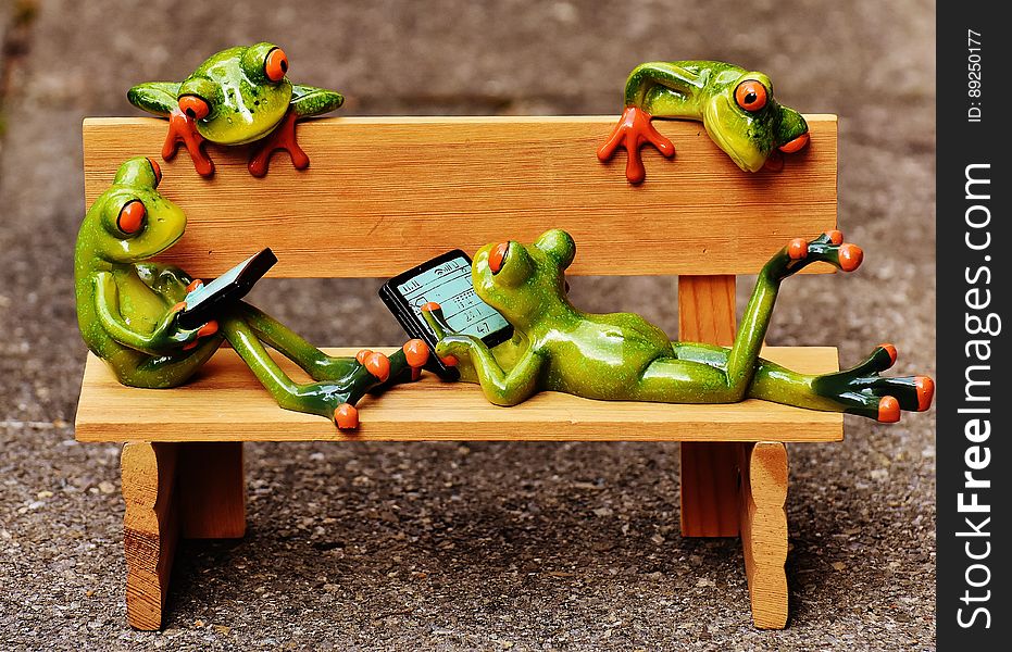 A miniature bench with ceramic frog statuettes. A miniature bench with ceramic frog statuettes.