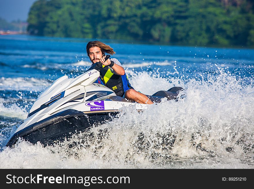 Man in Safety Vest Riding a Personal Watercraft during Daytime