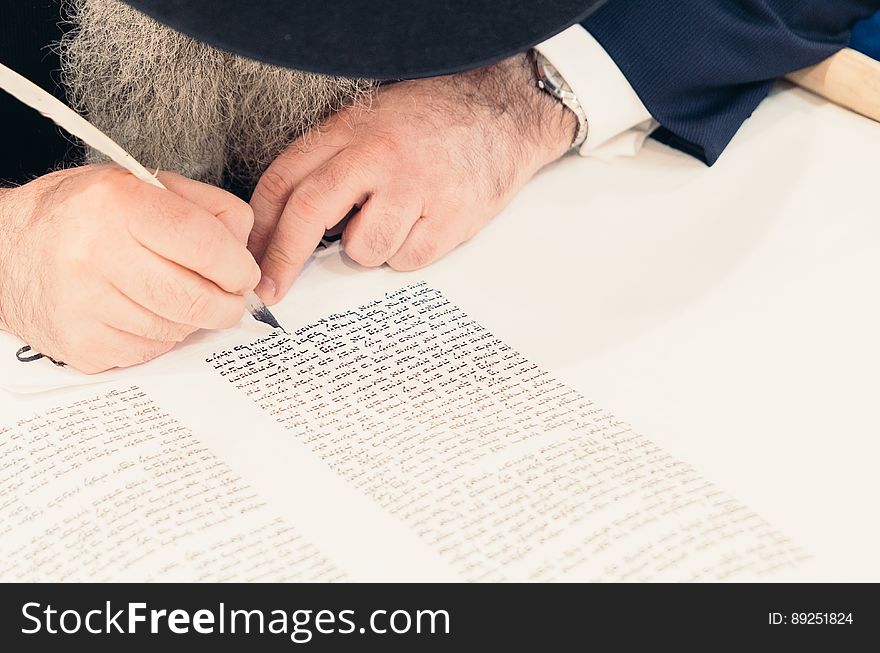 A bearded man writing with ink and a quill pen. A bearded man writing with ink and a quill pen.