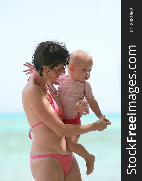 Mother touching baby hand at the beach