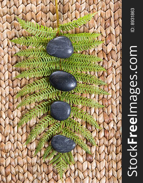 Zen Stones on a grass mat with a fern isolated on white
