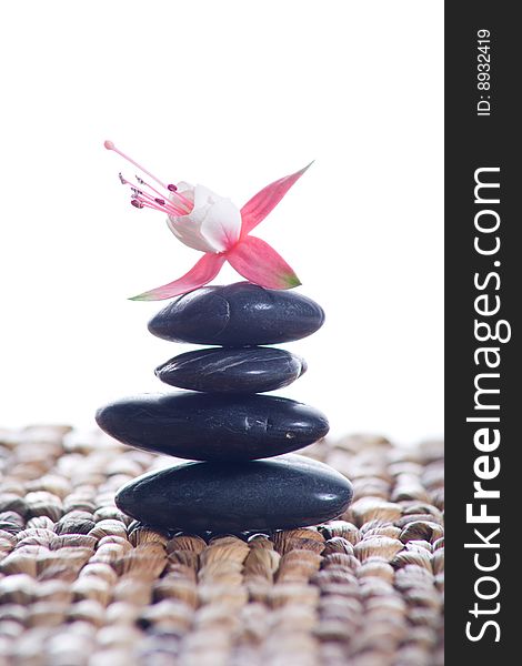 Zen stones with pink flowers on a grass matte