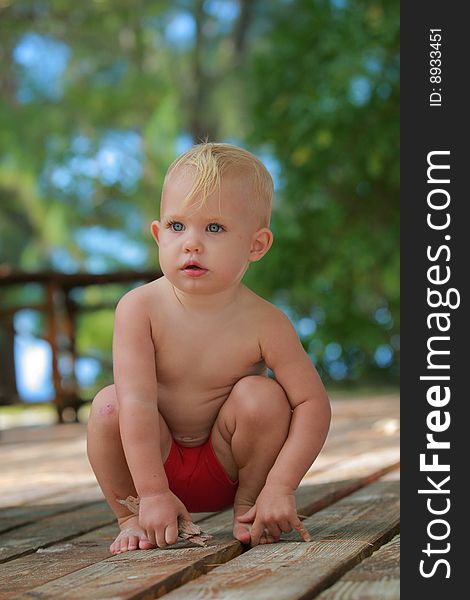 Baby playing on a wooden deck. Baby playing on a wooden deck