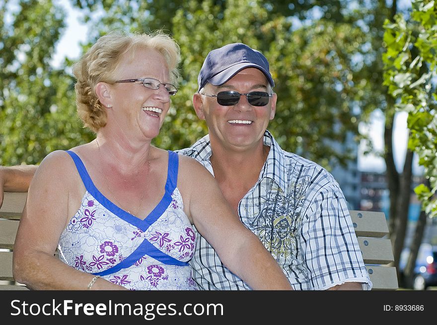 Aged couple sitting on a bench and laughing out loud