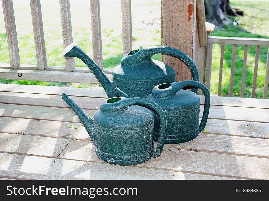 Three blue watering cans on front porch