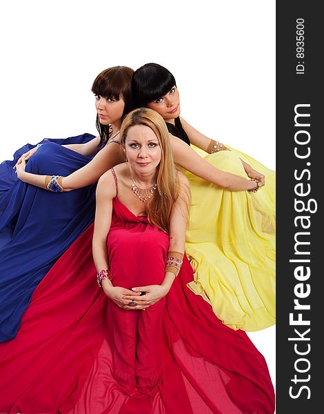 One blond and two brunette woman in red, blue, and yellow dresses. One blond and two brunette woman in red, blue, and yellow dresses