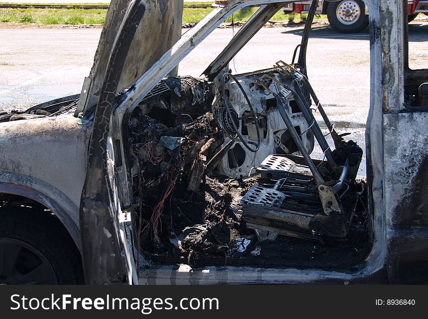 Interior of a burned out truck with fire truck in the background. Interior of a burned out truck with fire truck in the background